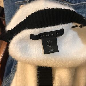 White sweater with black trim and gold buttons.